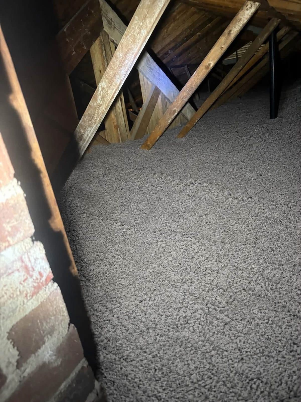 Clean new blown-in insulation installed to full depth in an attic corner