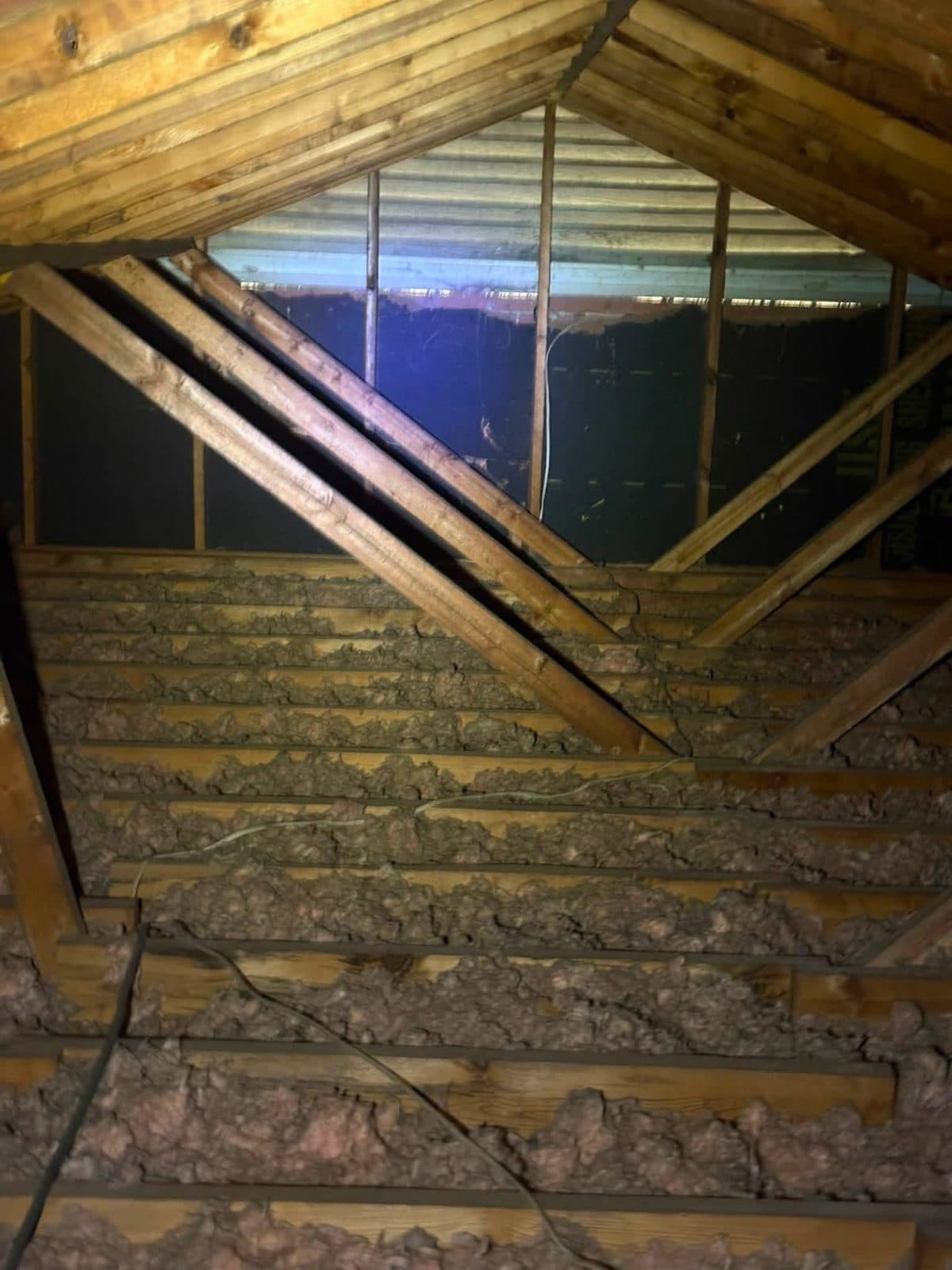 Aged, unevenly settled attic insulation before removal