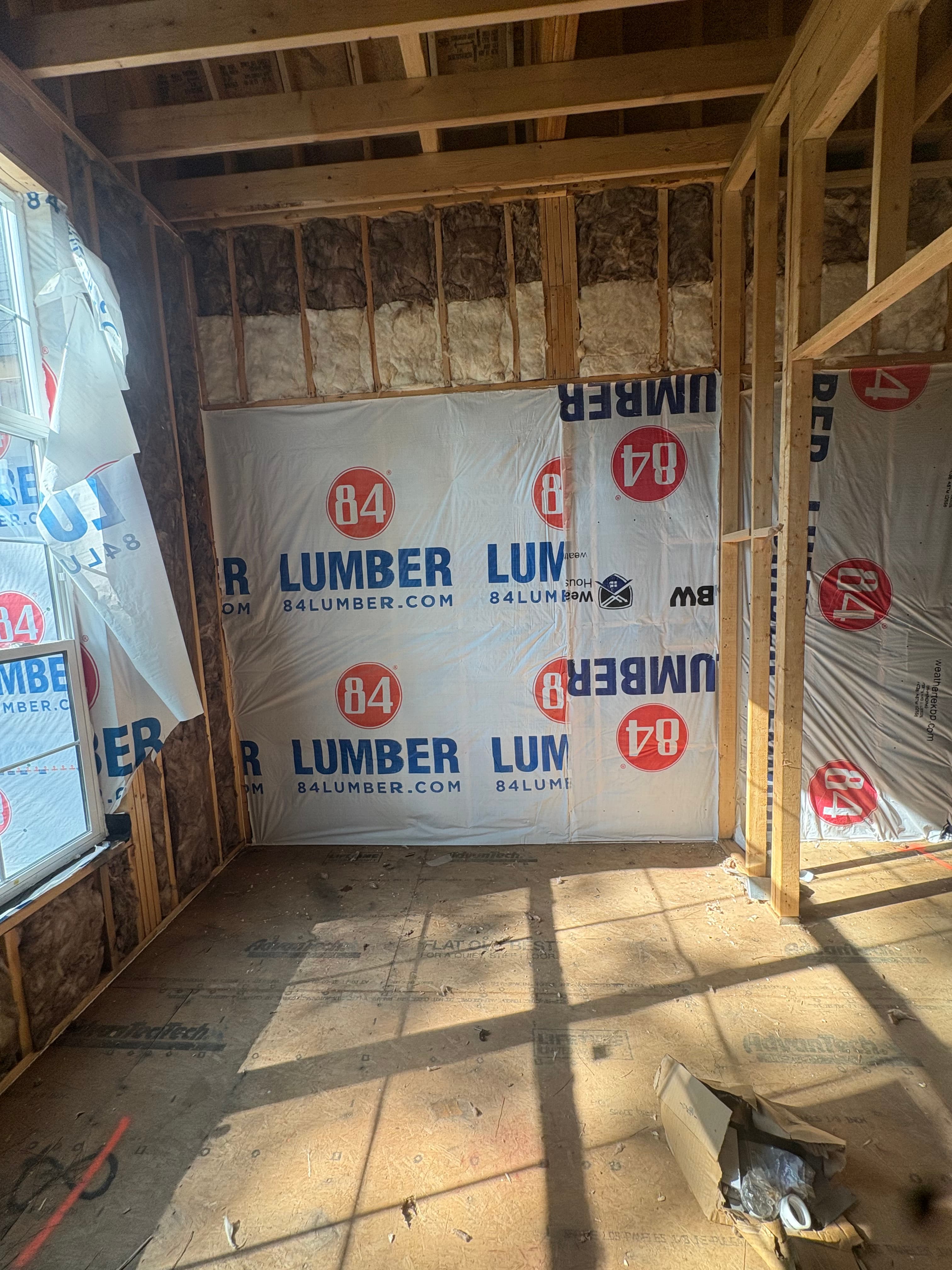 Batt insulation installed in a new-construction wall cavity with the house wrap visible from inside