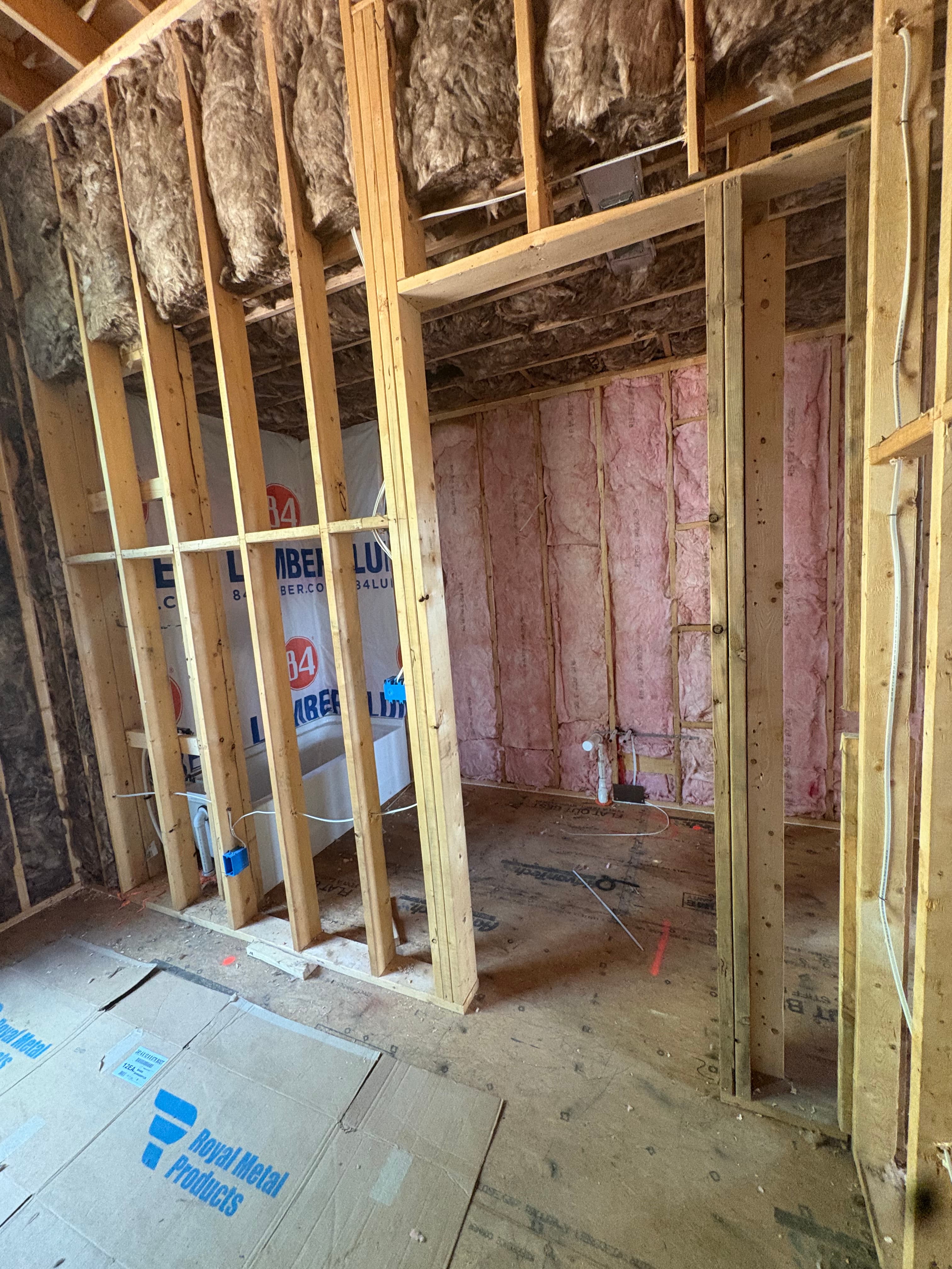Batt insulation fitted into ceiling and knee-wall framing around ductwork on a new-construction job