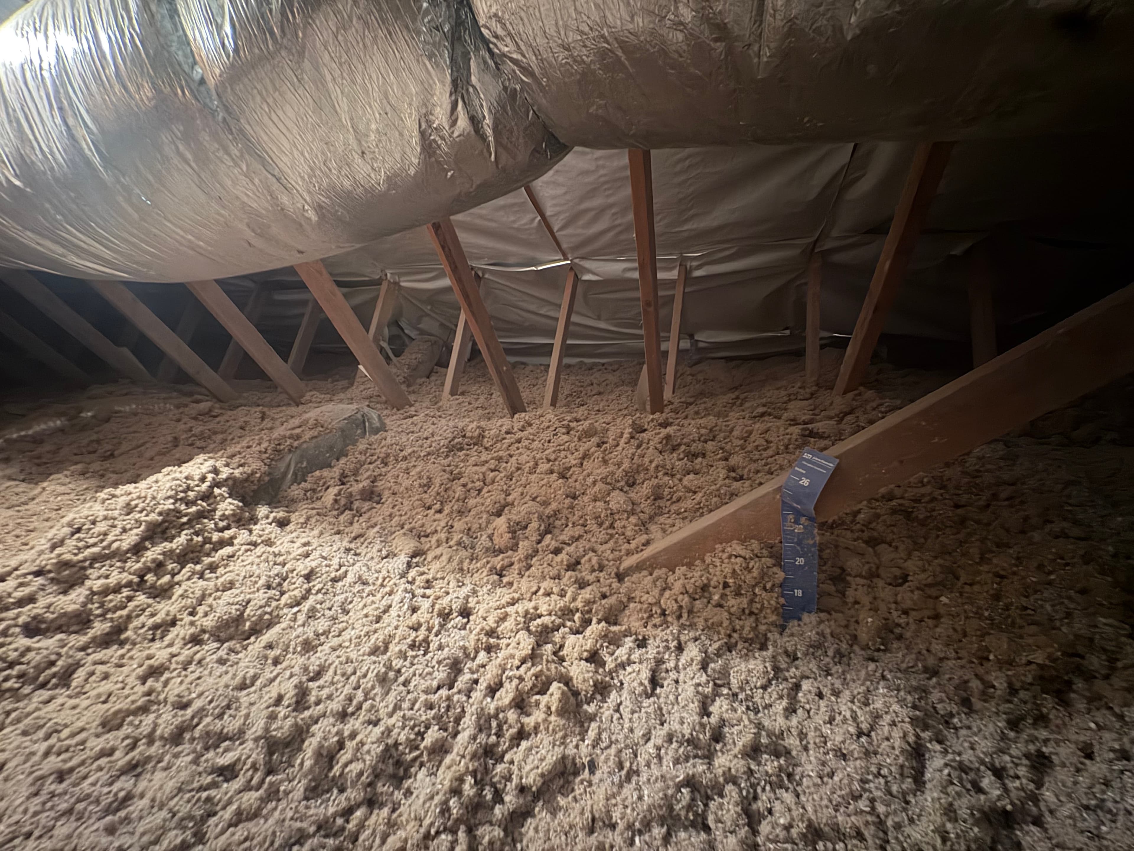 A depth gauge showing the finished depth of new blown-in insulation across a Charlotte-area attic floor