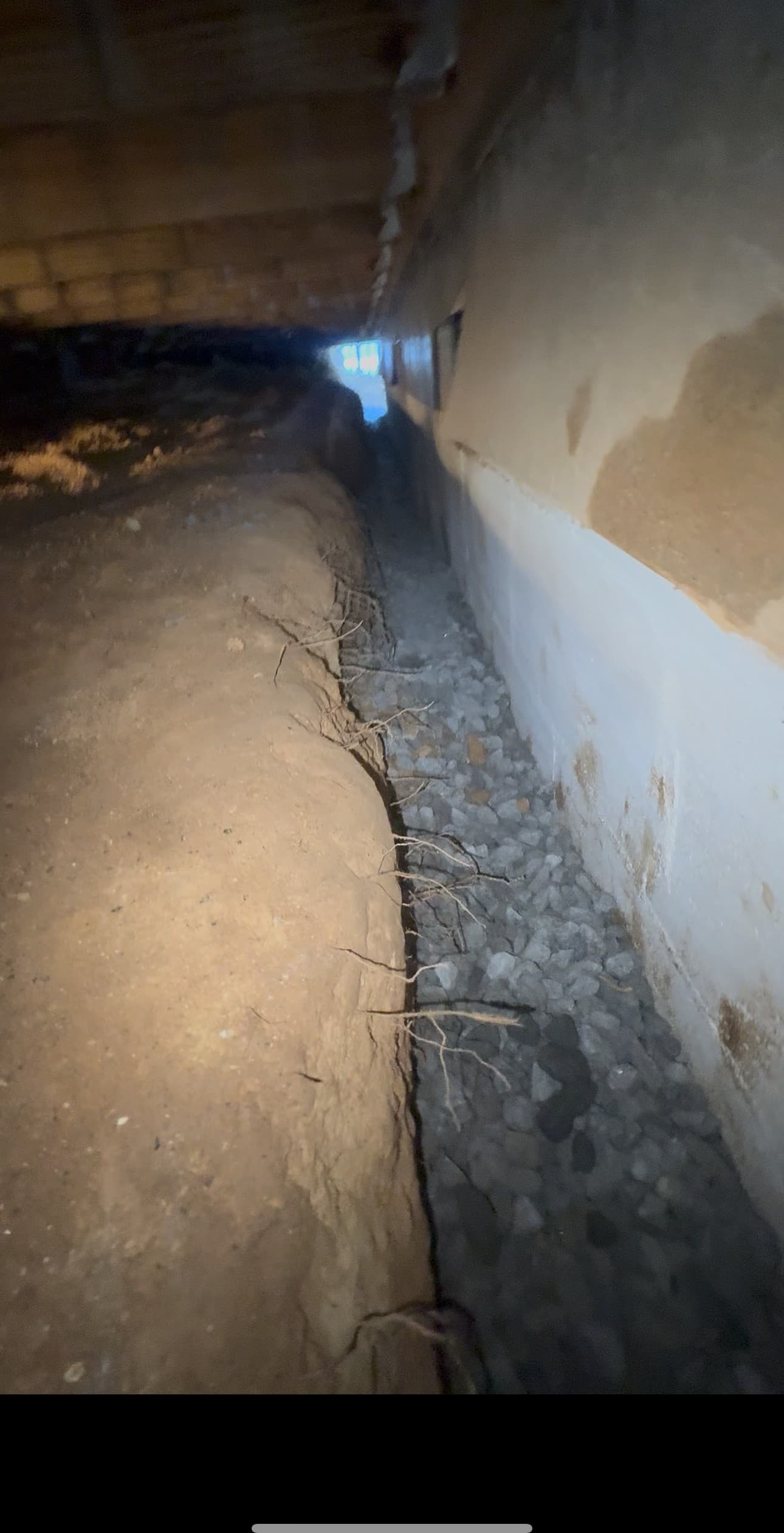 An interior drainage trench with gravel installed along a crawl space foundation wall
