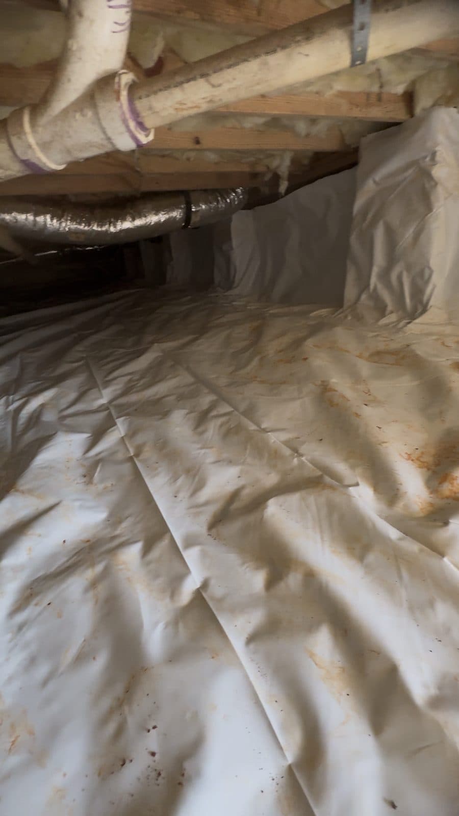 Reinforced vapor barrier draped across a crawl space floor and up the walls